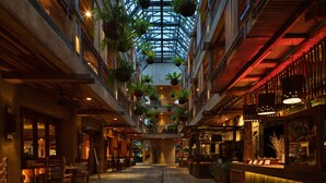 A hotel atrium with a high ceiling, hanging plants, wooden beams, and a central staircase. - Dinso Resort & Villas Ko Chang, Vignette Collection by IHG (Ko Chang)