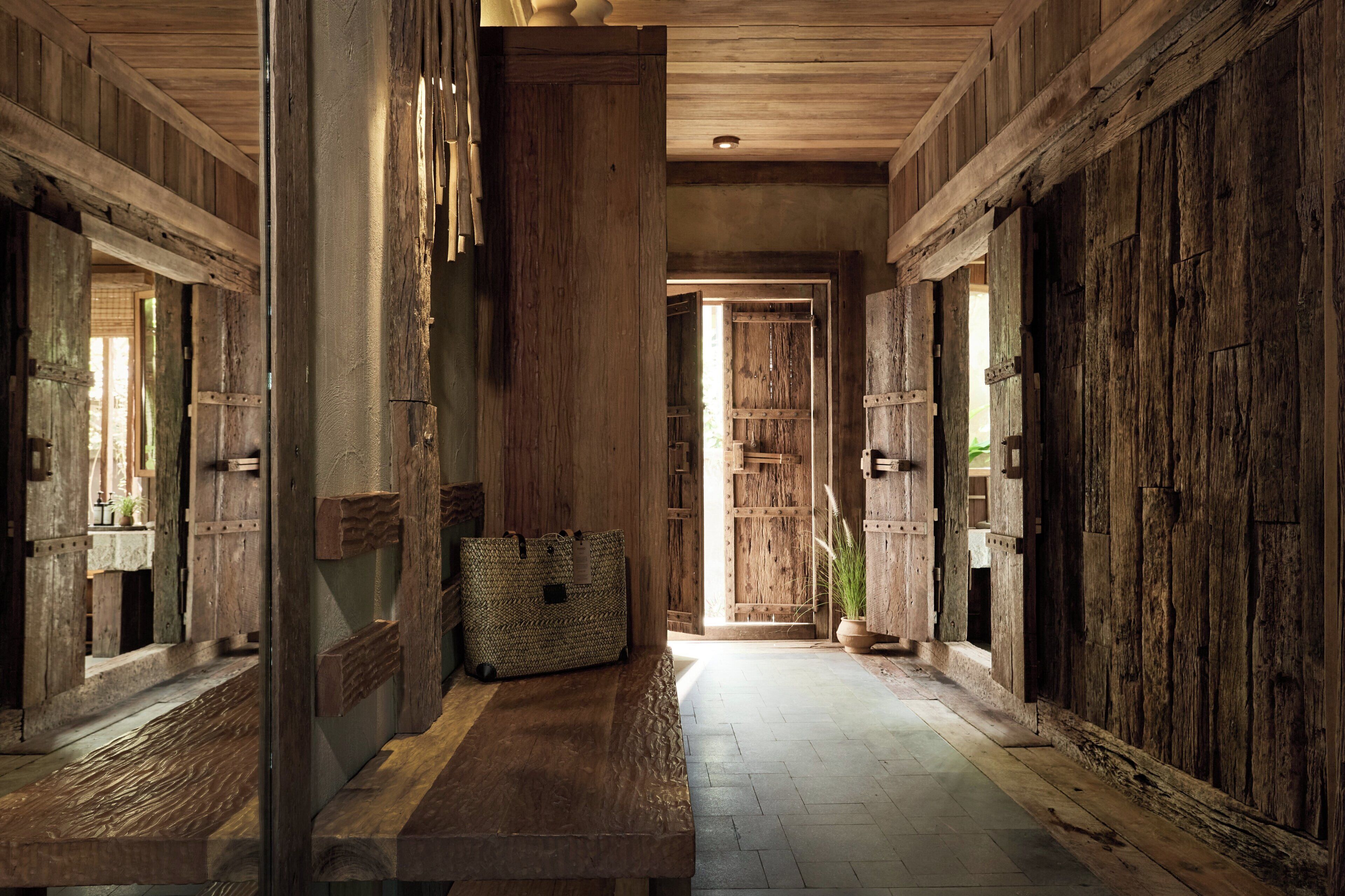 A rustic hallway with wooden doors and a bench.