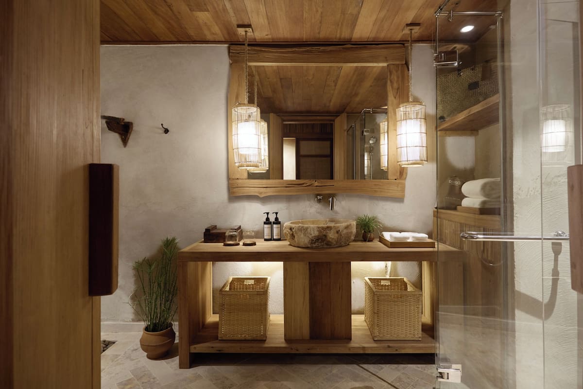 Un tocador de madera con un espejo grande, dos apliques de luz y un lavabo.