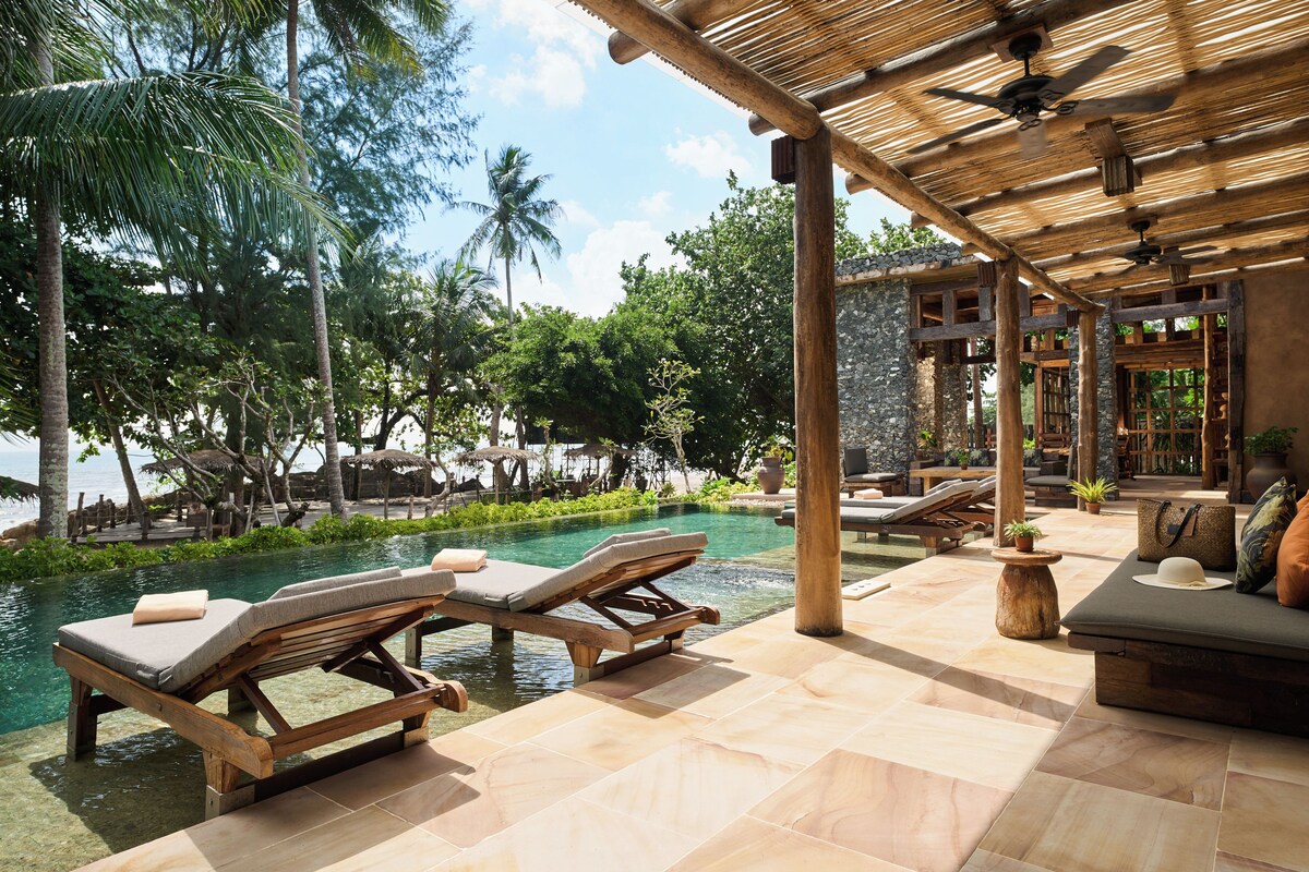 A poolside area with lounge chairs and a covered seating area.