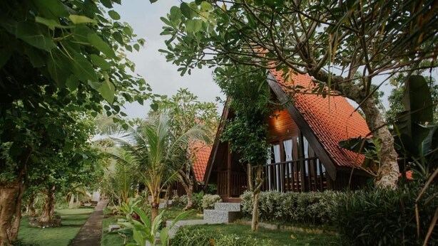 A tropical resort with a wooden house surrounded by lush greenery and a well-maintained garden. - Jun Cottage Nusa Penida (Penida Island)