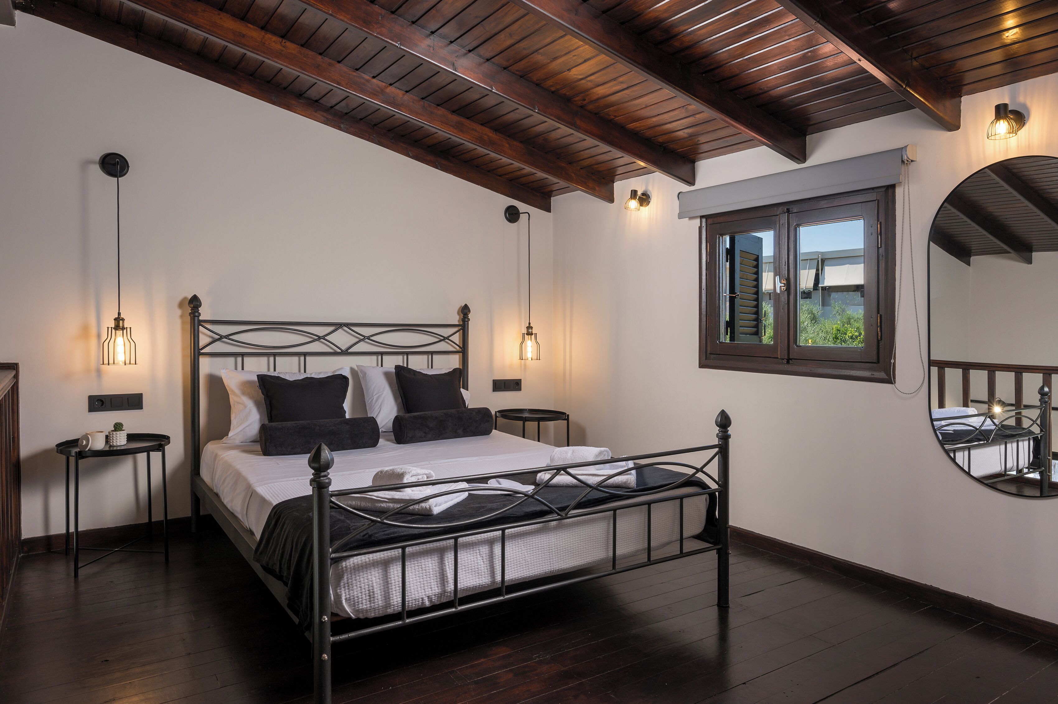 Une chambre à coucher avec un lit, des tables de chevet, une fenêtre et un miroir.