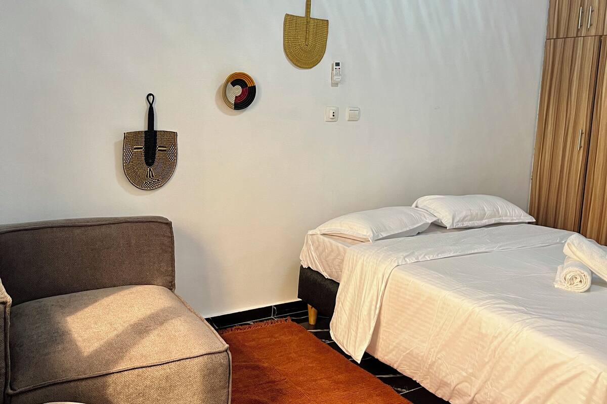 A bedroom with a bed, a sofa, a rug, and wall decorations.