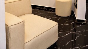A hallway with a black marble floor, a beige armchair, and a small round ottoman. - Casa Hôtel Résidence (Abidjan)