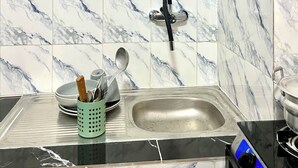 A kitchen with marble tiles, a stainless steel sink, and a green utensil holder. - Casa Hôtel Résidence (Abidjan)
