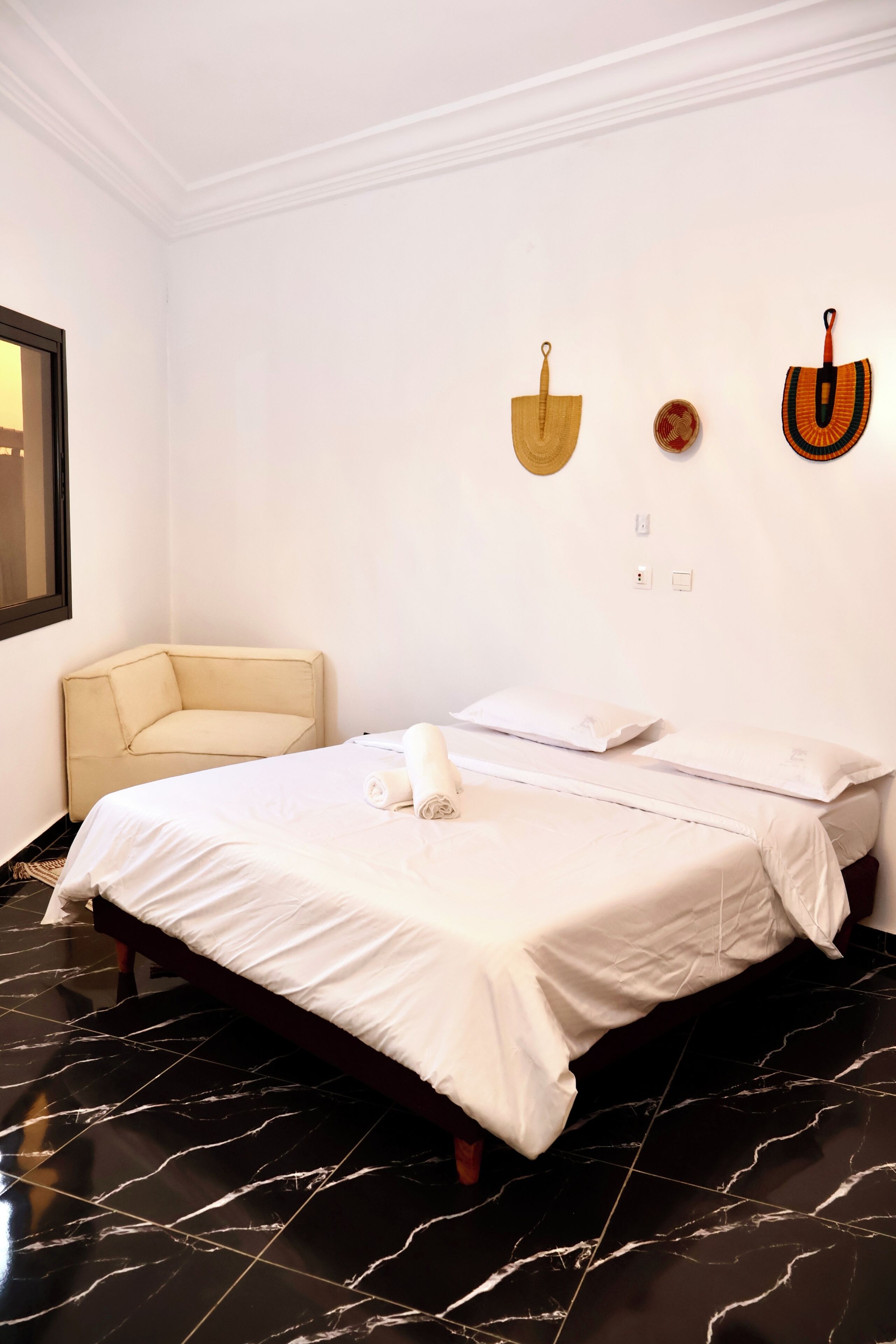A hotel room with a bed, a chair, and a wall with decorative items.