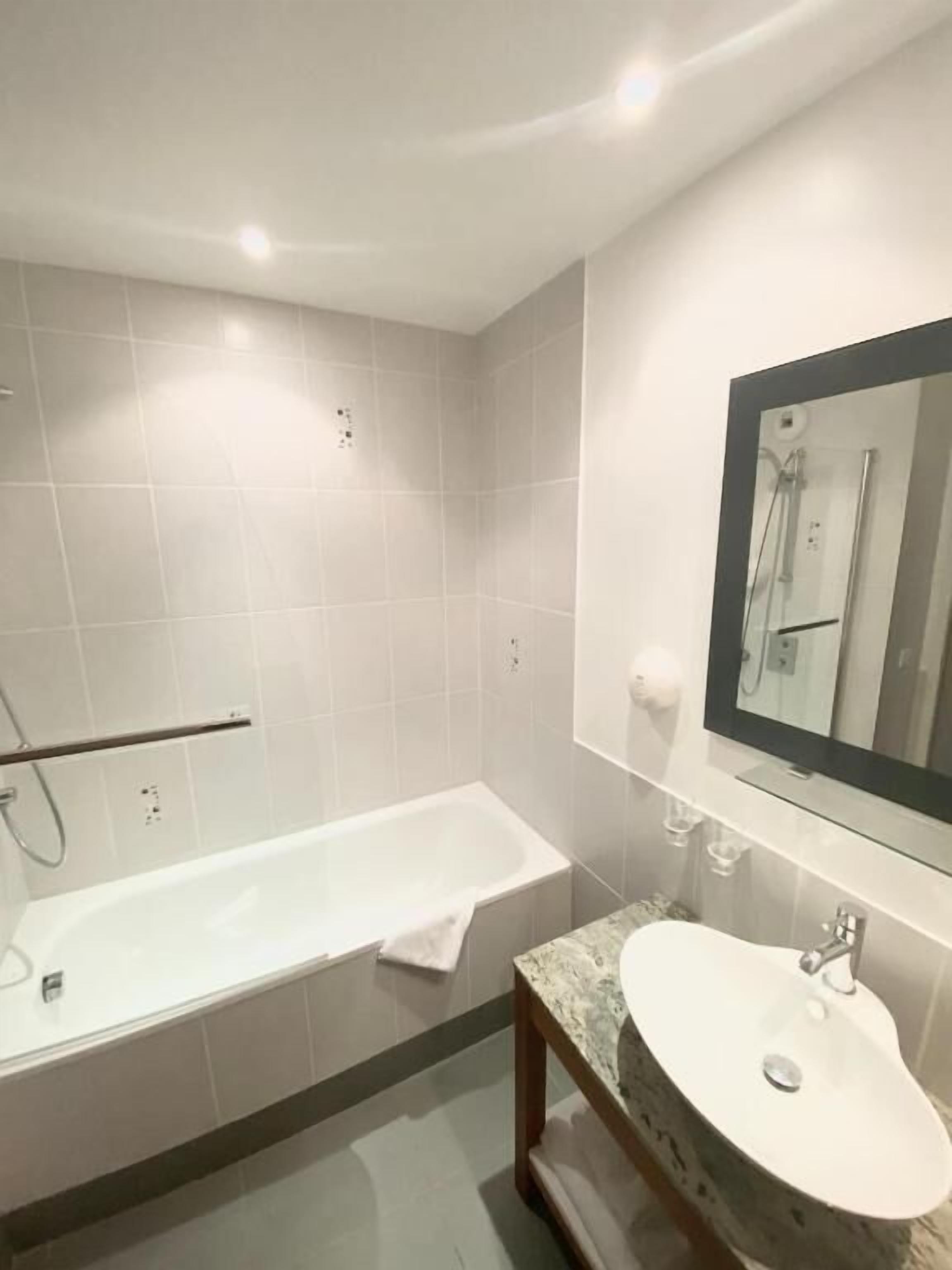 Une salle de bain moderne avec une baignoire, un lavabo et un miroir.