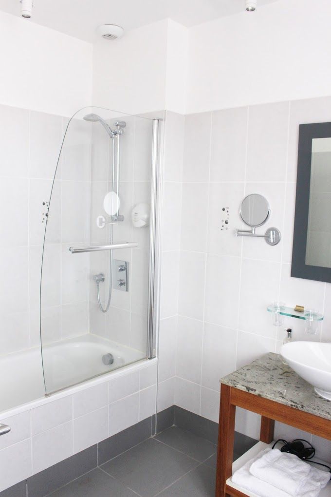 Un baño moderno con ducha de vidrio, tocador de madera con lavabo y espejo.