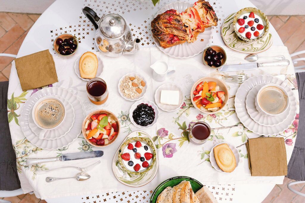 A table set for breakfast with various dishes, including fruits, pastries, and beverages.
