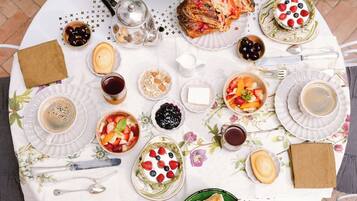 A table set for breakfast with various dishes, including fruits, pastries, and beverages.