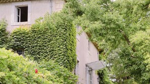 Een huis met een tuin, een trap die naar de ingang leidt, en een raam met gordijn.