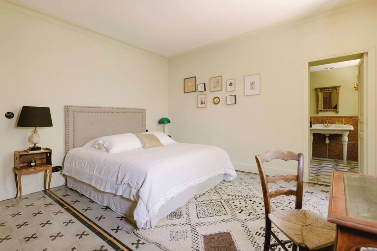 Une chambre à coucher avec un lit, une table de chevet avec une lampe, une chaise et un tapis à motifs.
