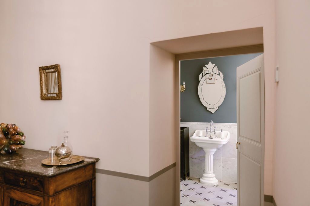 Un bagno con un mobile lavabo in legno, uno specchio e un elemento decorativo a parete.