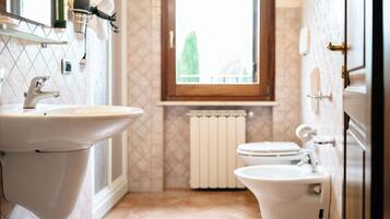 Kylpyhuoneessa on pesuallas, wc, bidee ja ikkuna, josta on näkymä vehreään maisemaan.