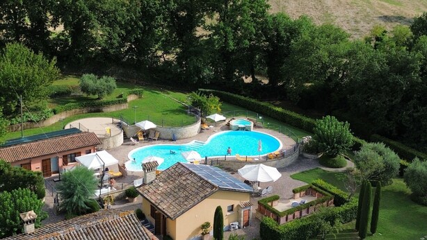 Eine Villa mit Swimmingpool, umgeben von üppiger Vegetation und Hügeln.