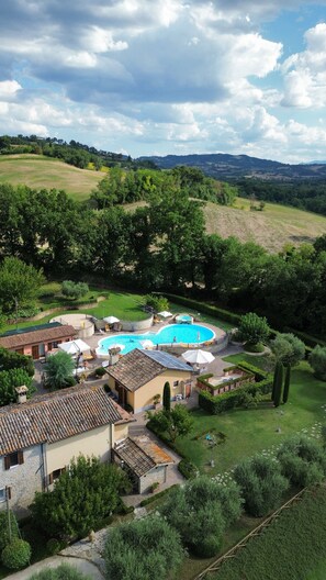 A villa with a swimming pool, surrounded by lush greenery and hills.