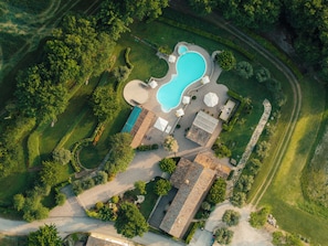 Vista aérea de una propiedad residencial con piscina, cancha de tenis y jardín ajardinado.