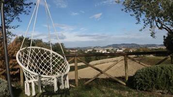 Una hamaca, valla de madera y vista a colinas distantes.