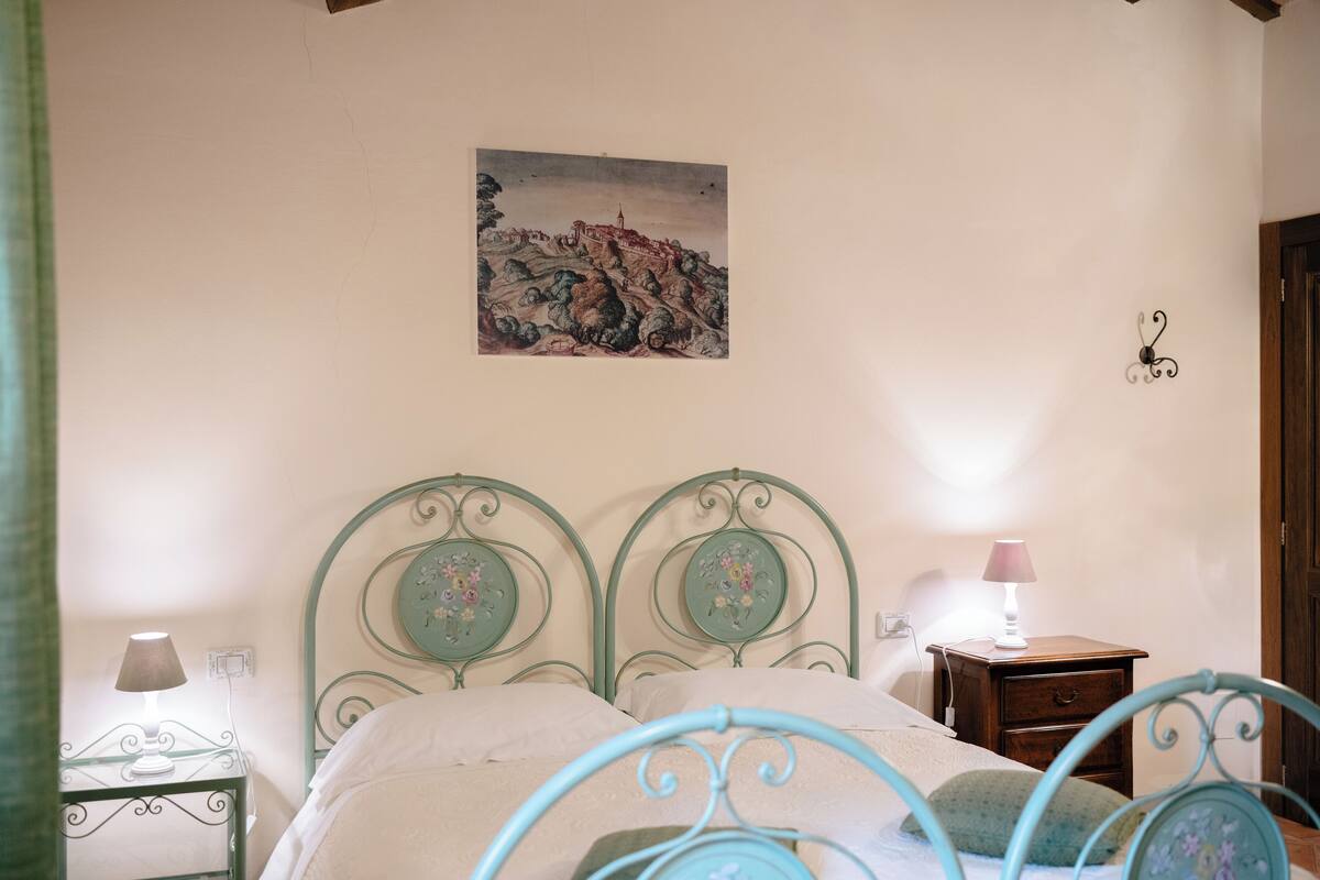 Ein Schlafzimmer mit einem Bett, einem Nachttisch, einer Lampe und einem Bild an der Wand.