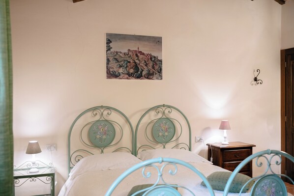 A bedroom with a bed, a nightstand, a lamp, and a painting on the wall.
