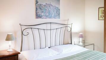 Ein Bett mit einem Metall-Kopfstück, ein Nachttisch mit einer Lampe und ein kleiner Nachttisch ebenfalls mit einer Lampe.