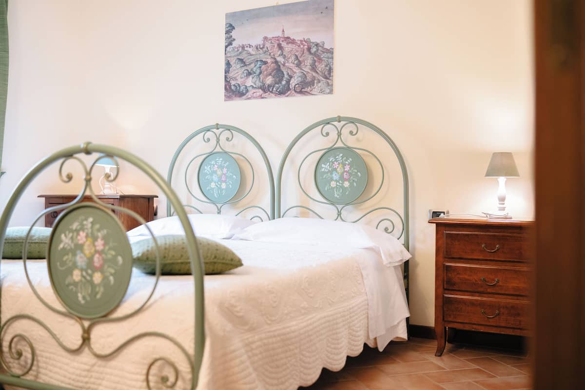 Ein Schlafzimmer mit Bett, Nachttisch, Schminktisch und einem Bild an der Wand.