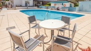 A swimming pool with a sun lounger and a table, surrounded by buildings. - Summer Haven, Polis: Sea & Mountain Views, Roof Terrace (Polis Chrysochous)