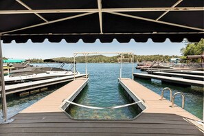 Uma marina com barcos atracados, uma rampa de lançamento de barco coberta e vista clara para a água.