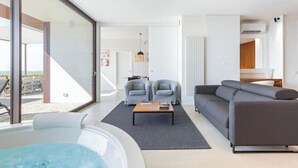 A modern living room with a glass door leading to an outdoor area, a sofa, two armchairs, and a coffee table. - House on the Langhe - Luxury private Pool, Sauna and Jacuzzi (Diano D'alba)