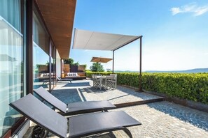 An outdoor patio with lounge chairs, a table, and a covered seating area. - House on the Langhe - Luxury private Pool, Sauna and Jacuzzi (Diano D'alba)