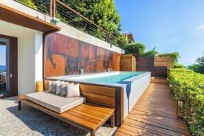 A modern outdoor swimming pool with a wooden deck and seating area. - House on the Langhe - Luxury private Pool, Sauna and Jacuzzi (Diano D'alba)