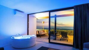 A modern hotel room with a large bathtub, a sofa, and a balcony with a view. - House on the Langhe - Luxury private Pool, Sauna and Jacuzzi (Diano D'alba)
