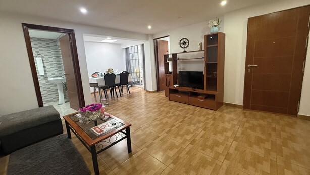 A living room with a sofa, coffee table, TV stand, and a dining area with chairs and a table. - Liudis House (Tijoco Bajo)