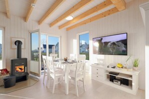 Enjoy a homey atmosphere with a dining table for meals, a wood-burning stove, and a flat-screen TV for entertainment.