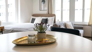 Una habitación de hotel con cama, sofá, planta en maceta, bandeja con vela y pañuelos de papel.