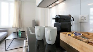 Una cocina moderna con una cafetera, dos tazas y una caja de madera con libros.