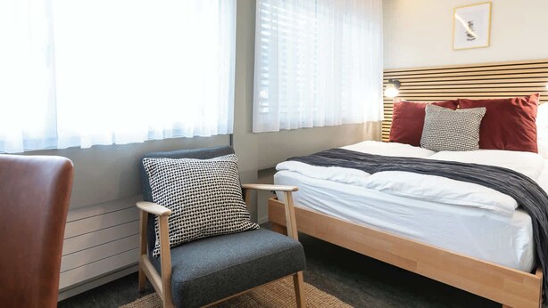 A bedroom with a bed, a chair, and a window with curtains. - Central St. Gallen Studio (yellow): Fast WiFi & kitchen for shared use (St. Gallen)