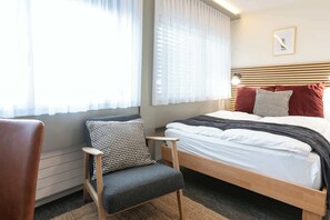 Ein Schlafzimmer mit Bett, Stuhl und einem fensterbepflanzten Fenster.