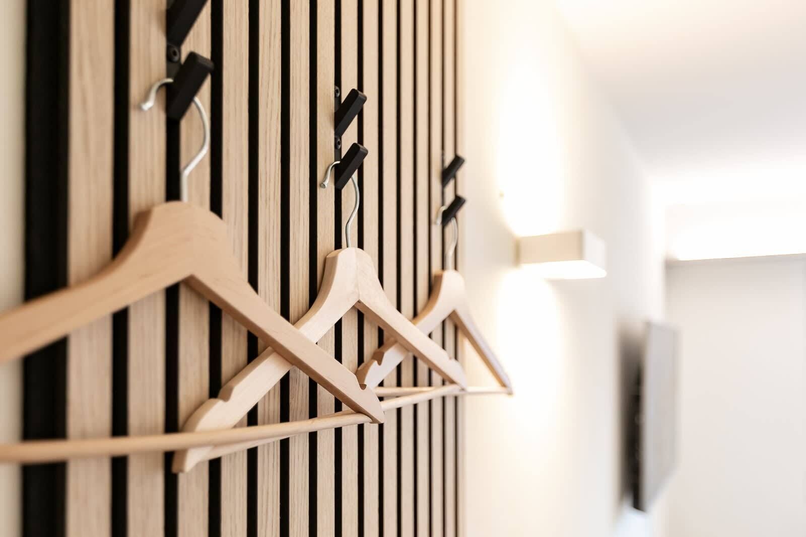 Un porte-objets en bois fixé au mur, doté de plusieurs crochets, un écran de télévision et un motif de lattes verticales en bois.