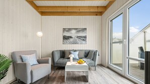 A modern living room with a grey sofa, a white coffee table, and a large window.