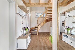 A modern interior with a wooden staircase, white cabinetry, and a view to the outside. - Kiek Inn - Infrared sauna, fireplace, bathtub, terrace, beach chair, parking (Olpenitz)