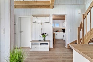 Une cuisine moderne avec des meubles blancs, un plancher en bois et une vue sur la salle à manger.