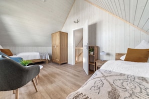 Ein gemütliches Schlafzimmer mit zwei Betten, einem Holzschrank, einem Schreibtisch und einem Stuhl.
