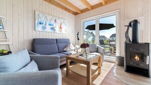 A cozy living room with a sofa, a coffee table, and a fireplace. - Kiek Inn - Infrared sauna, fireplace, bathtub, terrace, beach chair, parking (Olpenitz)