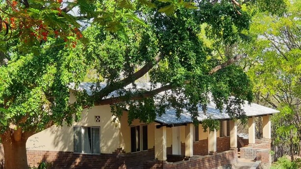 A two-story building with a covered porch and a staircase leading to the entrance. - Binga Rest Camp (Binga)