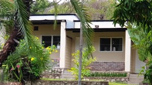 A house with a stone wall, a porch, and a staircase leading to the entrance. - Binga Rest Camp (Binga)