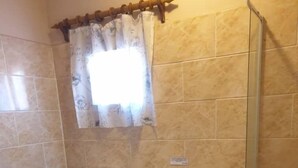 A bathroom with a toilet, sink, shower, and a window with a curtain. - Binga Rest Camp (Binga)