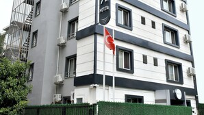 Un hotel moderno con fachada blanca y gris, varias ventanas y una bandera.