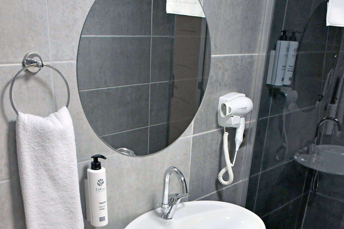 Ein Badezimmer mit rundem Spiegel, weißem Waschbecken und Handtuchhalter.