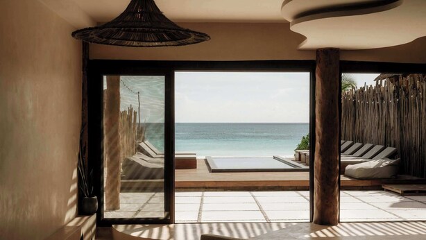 A spacious room with a large sliding glass door leading to a private outdoor area with a pool and lounge chairs. - Villa Privada | Fully-Staffed Beachfront Getaway (Tulum)